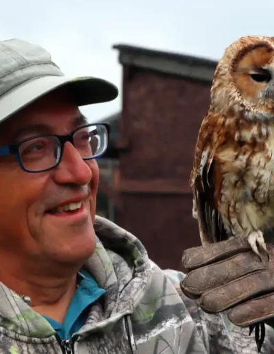 Amazing. Man admiring our tawny owl up close while he hold it on his fist.